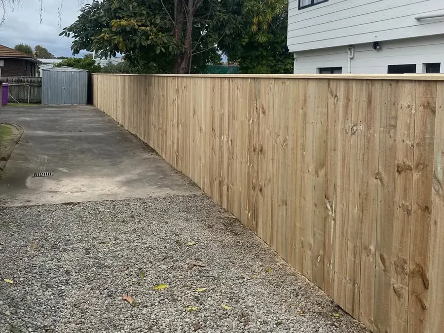 Long timber paling fence beside a driveway built by Rowdy Builders