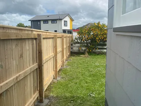 Capped timber fence with rails beside a house, Palmerston North