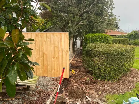 Timber fence going up beside a hedge, Palmerston North