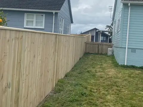 New timber boundary fence along a lawn beside a neighbouring house